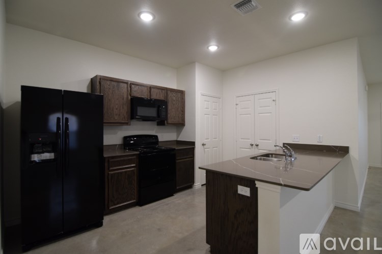 A kitchen with a black fridge, microwave, and cabinets.