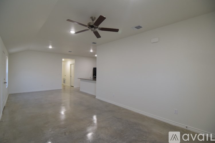 A spacious room with a ceiling fan and a concrete floor.
