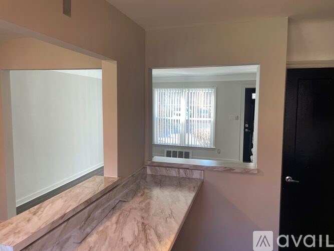 A room with a marble countertop and a window with blinds.