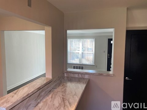 A room with a marble countertop and a window with blinds.