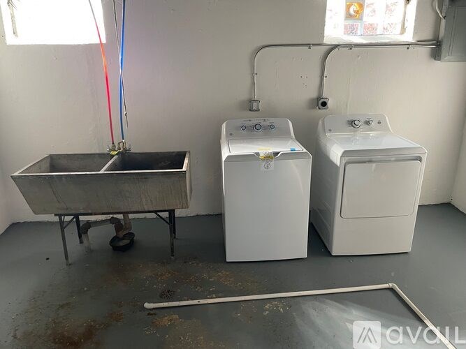 A white washing machine sits next to a white dryer in a room with a metal tub.