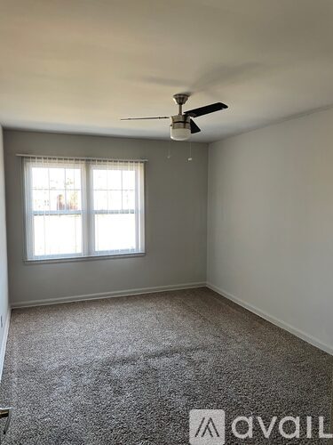 A room with a ceiling fan and a window.