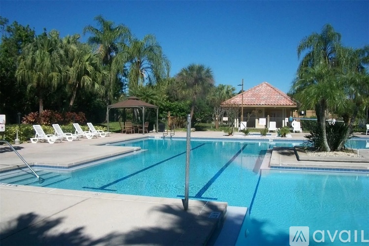 A pool with sun loungers and a gazebo in the background.