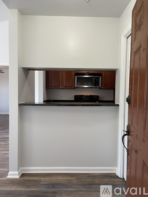 A kitchen with a brown door and a microwave above the stove.