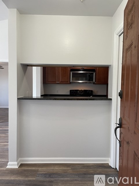 A kitchen with a brown door and a microwave above the stove.