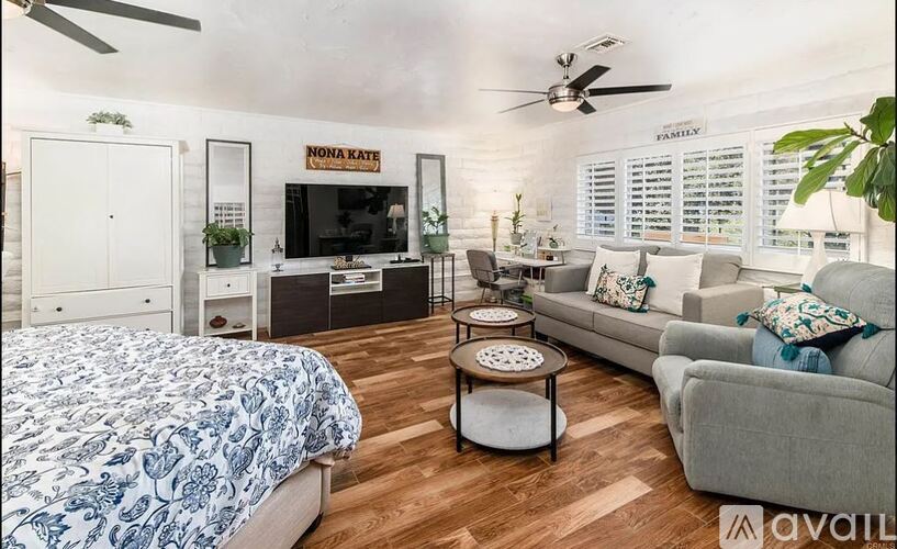 A bedroom with a bed, a couch, a coffee table, and a ceiling fan.