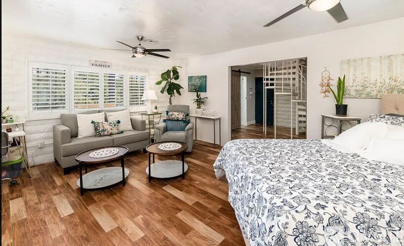 A bedroom with a bed, couch, and a ceiling fan.