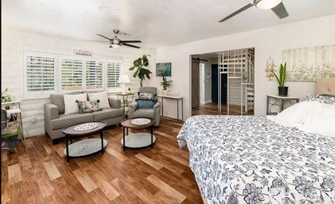 A bedroom with a bed, couch, and a ceiling fan.