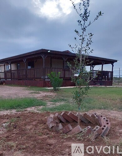 A house with a porch and a tree in front of it.