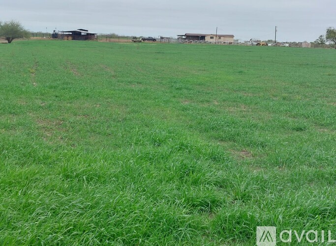 A field of green grass with a building in the distance.