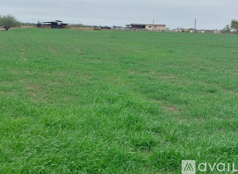 A field of green grass with a building in the distance.