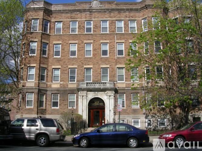 A tall building with a red door and a balcony in front.