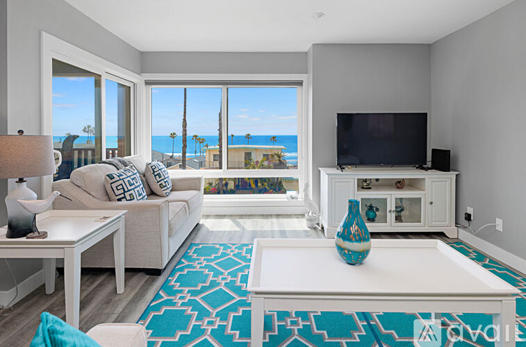 A living room with a large window overlooking the beach.