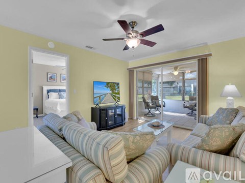 A living room with a striped couch and a ceiling fan.