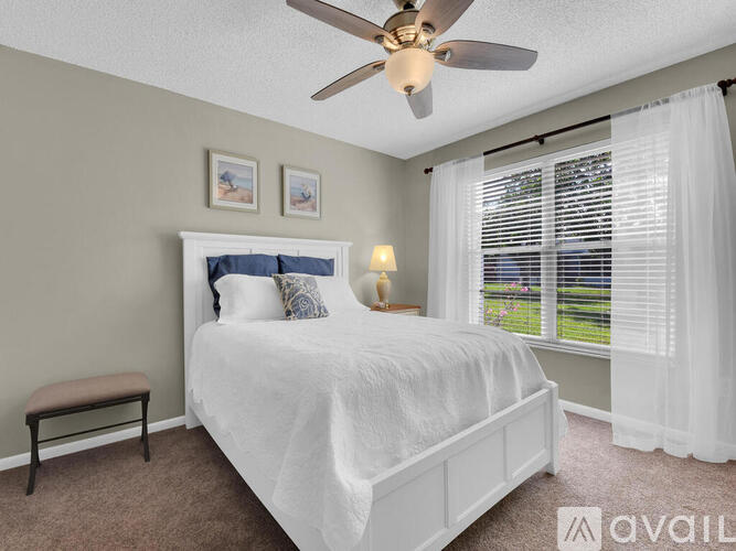 A bedroom with a white bed and a ceiling fan.