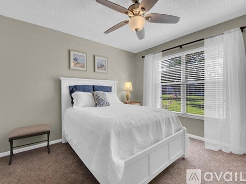 A bedroom with a white bed and a ceiling fan.