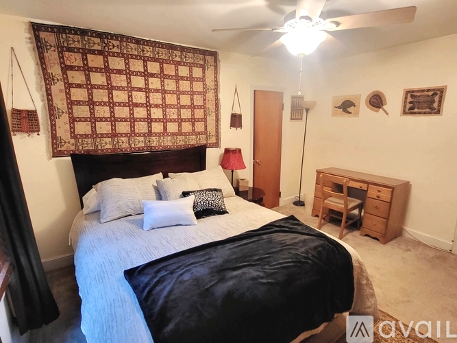 A bedroom with a bed, a ceiling fan, and a wooden cabinet.