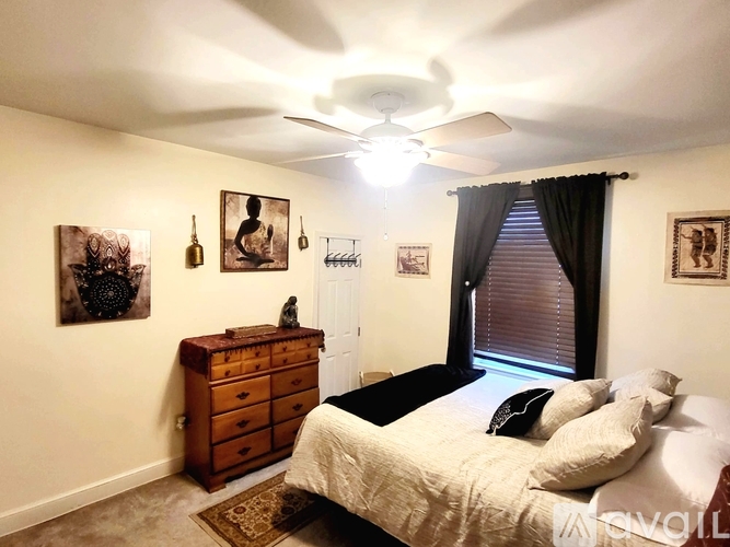A bedroom with a bed, dresser, and pictures on the wall.