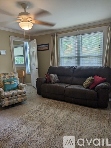 A living room with a couch, chair, and a fan.