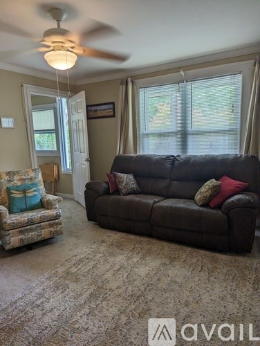 A living room with a couch, chair, and a fan.
