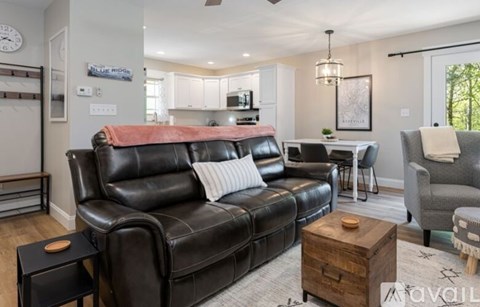 A living room with a black leather couch and a wooden coffee table.