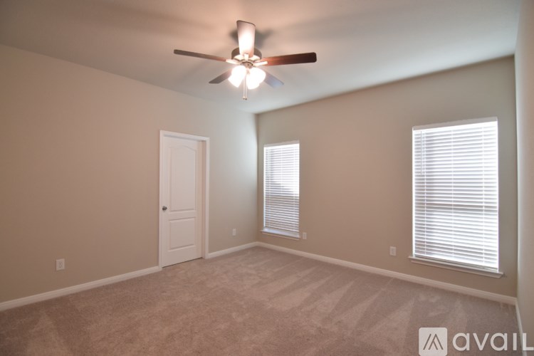 A room with a ceiling fan and two windows.