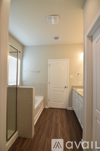 A bathroom with a white door and a wooden floor.