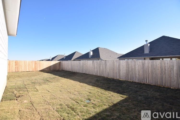 A backyard with a wooden fence and houses in the background.