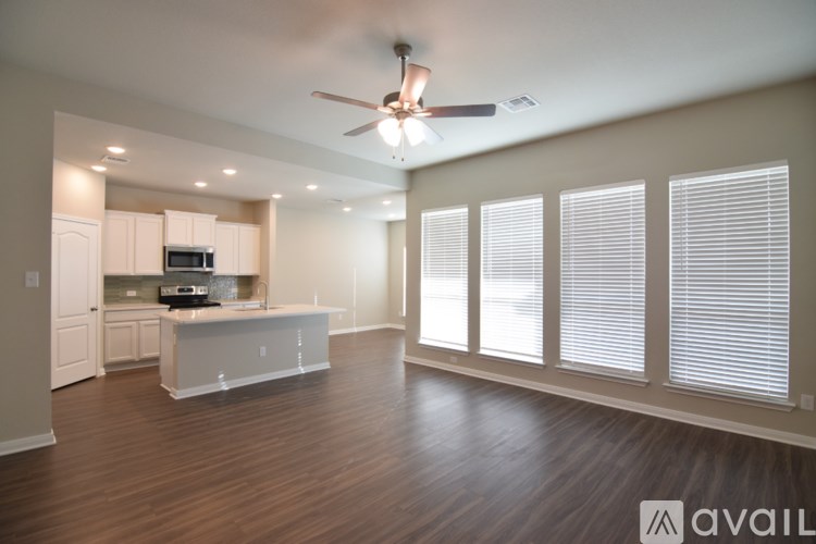 A spacious living room with a kitchen area in the background.