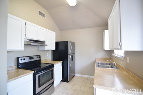 A kitchen with black appliances and white cabinets.