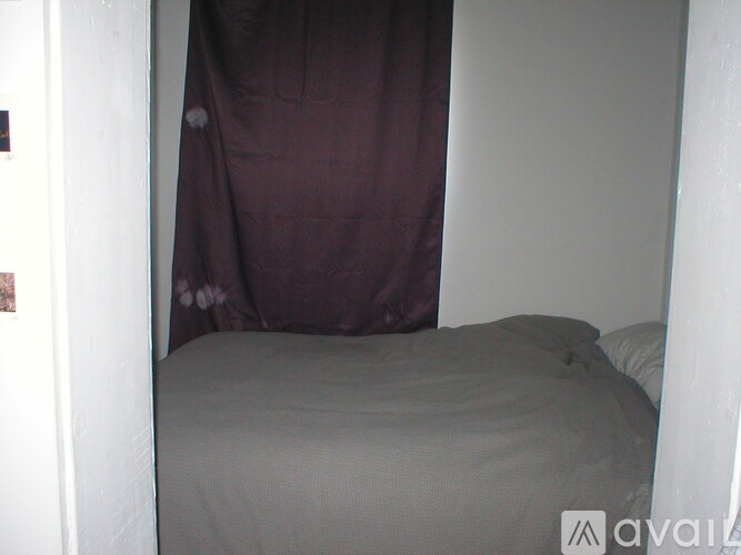 A bed with a grey sheet and a brown blanket.