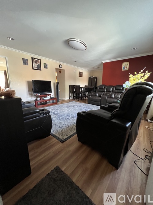 A living room with black leather furniture and a flat screen TV.