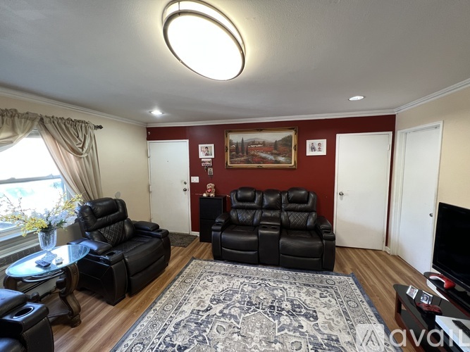 A living room with black leather furniture and a red wall.