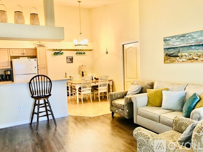 A kitchen with a white fridge and a dining table with chairs.