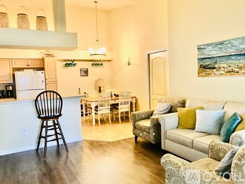 A kitchen with a white fridge and a dining table with chairs.