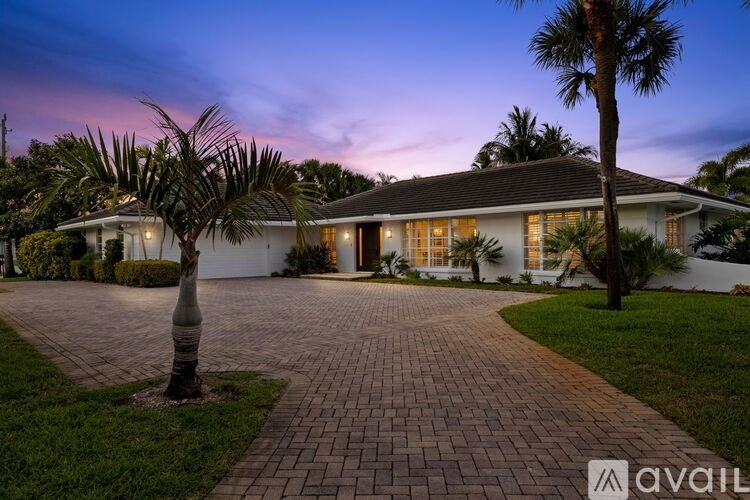 A house with a driveway and palm trees in front.