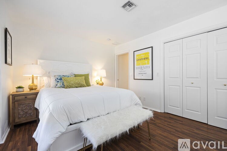 A bedroom with a white bed and a white furry chair.