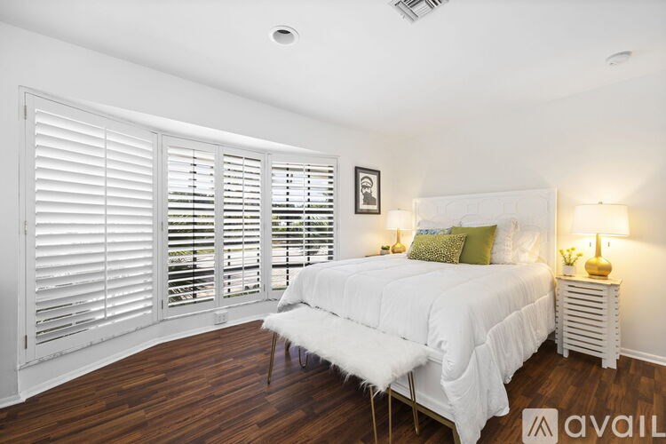 A bedroom with a bed, nightstand, and window with blinds.