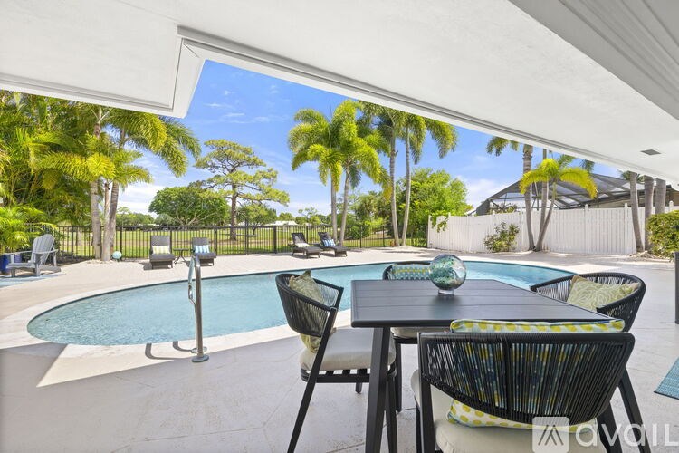 A patio with a table and chairs overlooking a pool.