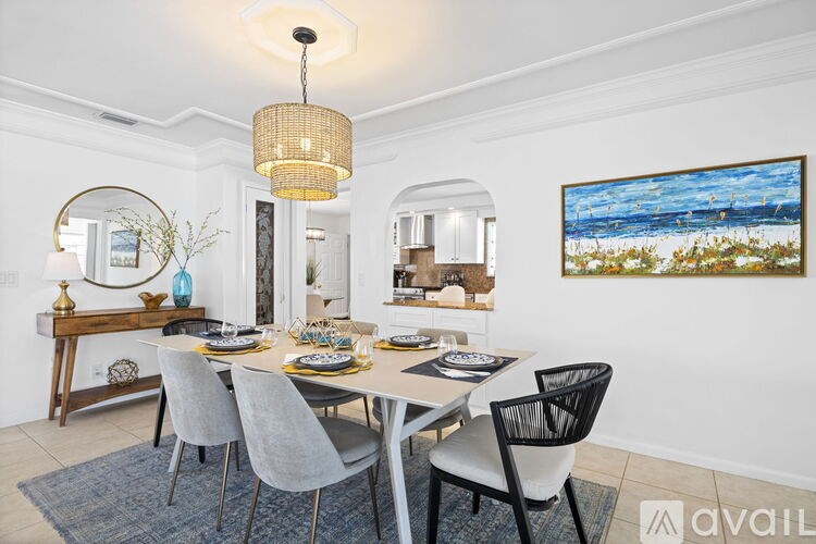 A dining room with a white table and grey chairs.