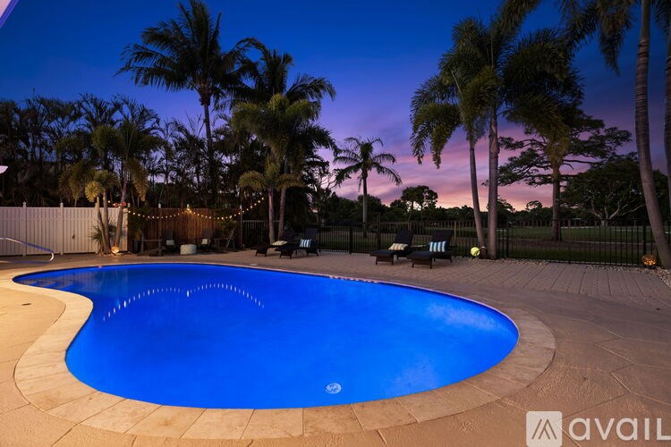 A swimming pool surrounded by palm trees at dusk.