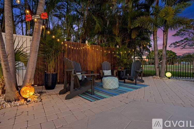A patio area with a striped rug, a couple of chairs and a table.