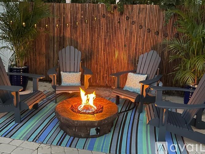 A fire pit in the middle of a striped rug with two chairs on either side.