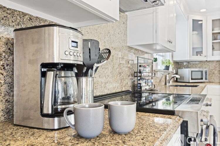 A coffee maker with two cups on a countertop.