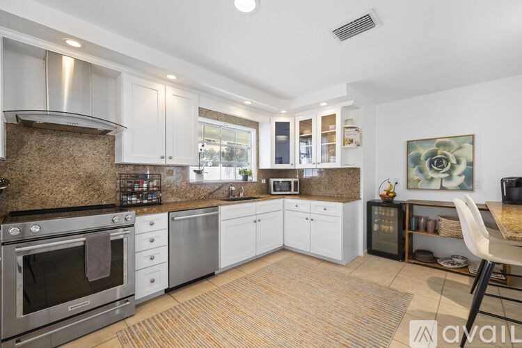 A kitchen with a stainless steel oven and white cabinets.