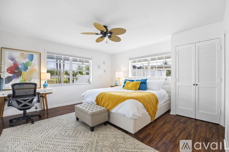 A bedroom with a bed, a chair, and a ceiling fan.