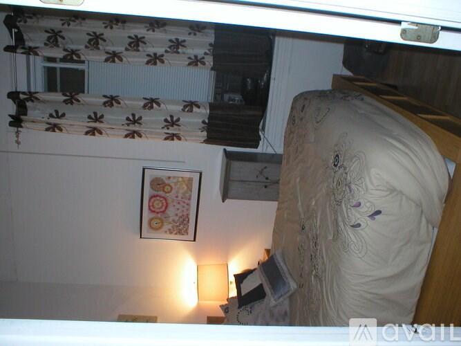 A bedroom with a bed, nightstand, and a picture on the wall.