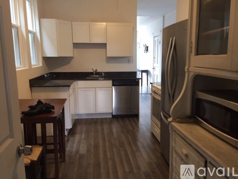 A kitchen with white cabinets and a black countertop.