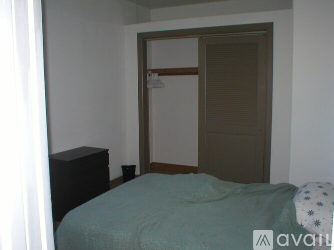 A bedroom with a bed, nightstand and closet.