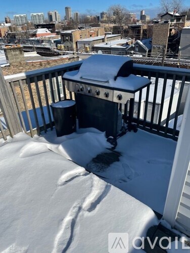A BBQ grill on a snow-covered balcony.